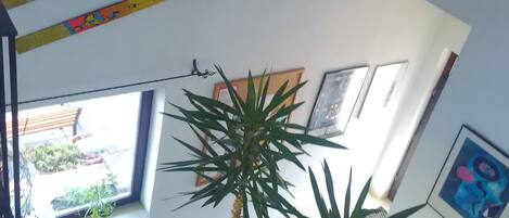 A staircase with a railing, a potted plant, and a painting on the wall.