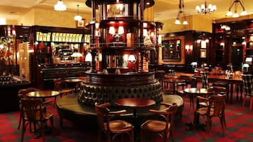 A bar area with multiple seating arrangements, including round tables and chairs, and a central bar counter.