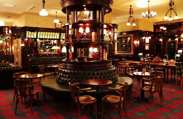 A bar area with multiple seating arrangements, including round tables and chairs, and a central bar counter. - New Falcon Palas  (Istanbul)