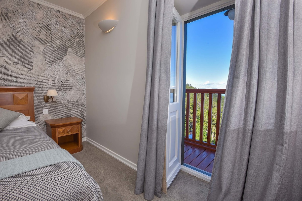 A bedroom with a bed, nightstand, and a view of a balcony.