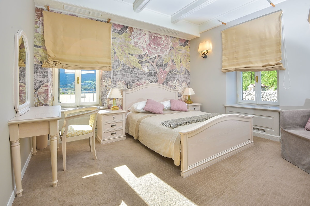 A bedroom with a bed, bedside tables, a desk, and a chair.