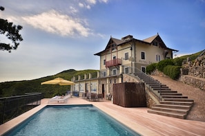 Un hotel con piscina, mobiliario exterior y una escalera que conduce a la entrada.