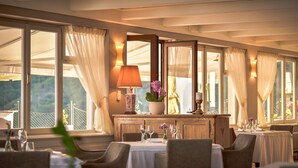A dining area with tables set for guests, a wooden buffet, and large windows with curtains. - Hotel Draga di Lovrana (Lovran)