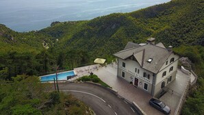 A hotel with a swimming pool, surrounded by lush greenery and a view of a large body of water. - Hotel Draga di Lovrana (Lovran)