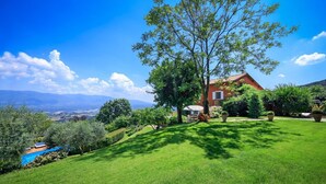 A house with a red roof, surrounded by a well-maintained lawn and trees. - Verdidea - VILLA NAPOLEONE (Rignano sull'Arno)