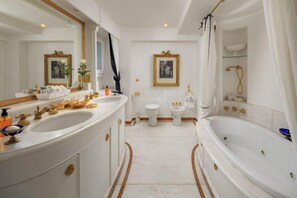 A luxurious bathroom with a large white bathtub, a double sink vanity, and a separate toilet.