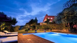 A swimming pool with lounge chairs, a stone patio, and a large house in the background. - Verdidea - VILLA NAPOLEONE (Rignano sull'Arno)