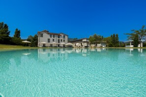 Una piscina cristalina con un edificio al fondo.