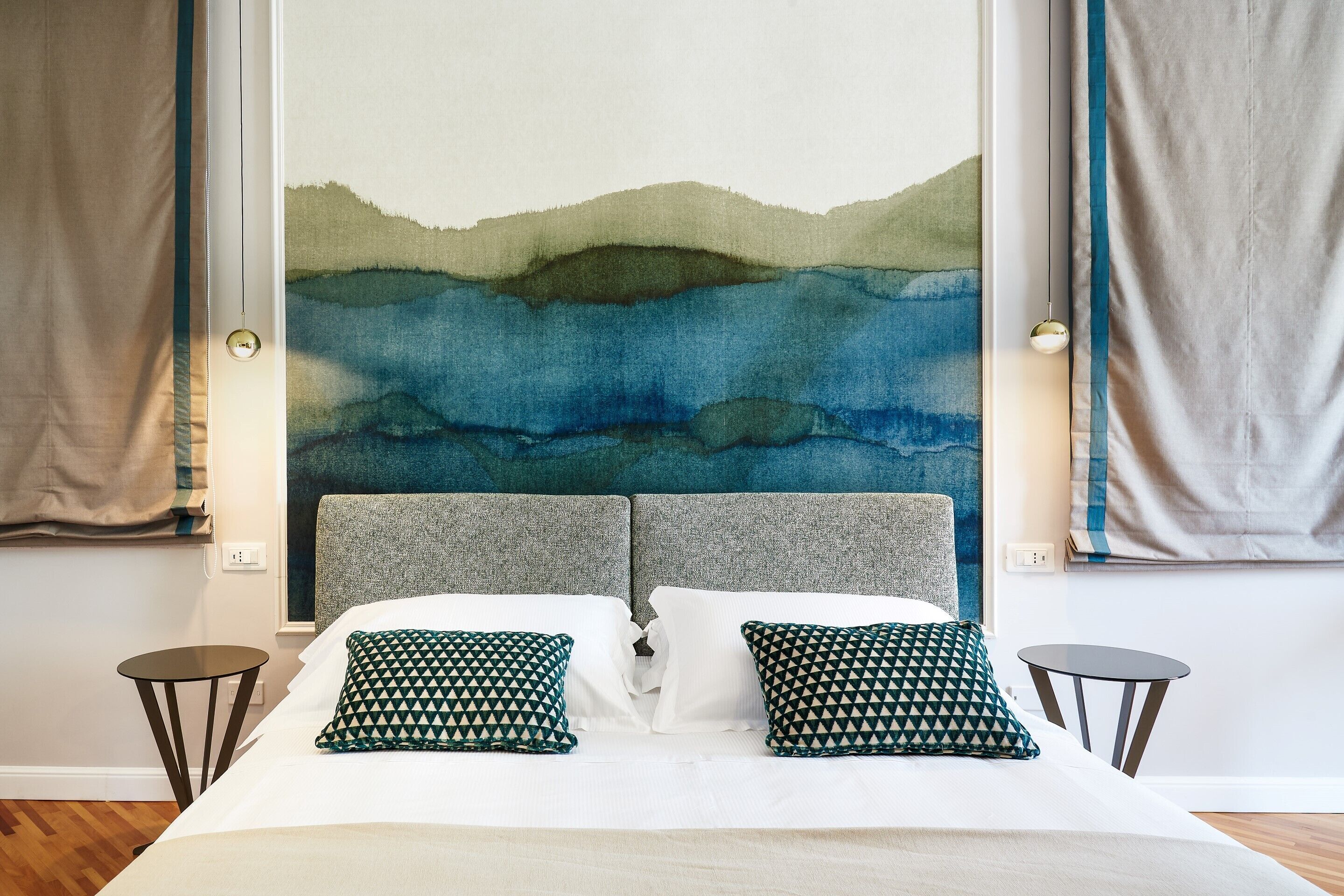 A bed with two pillows, a headboard, and a wall painting.