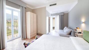 A hotel room with a bed, a sofa, a wardrobe, and a balcony with a view.