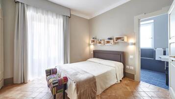 Ein Hotelzimmer mit Bett, Stuhl, Nachttisch und einem durchgegangenen Tür sichtbaren Badezimmer.
