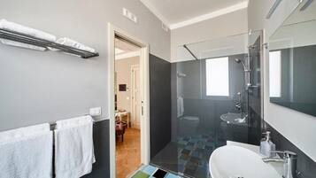 Une salle de bain moderne avec une douche à parois de verre, un lavabo blanc et un sol carrelé.