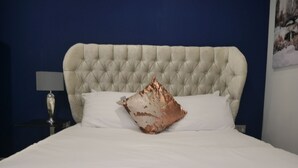 A bed with a tufted headboard, white bedding, and a decorative pillow. - Milburn House  Luxury Apartments (Milton Keynes)