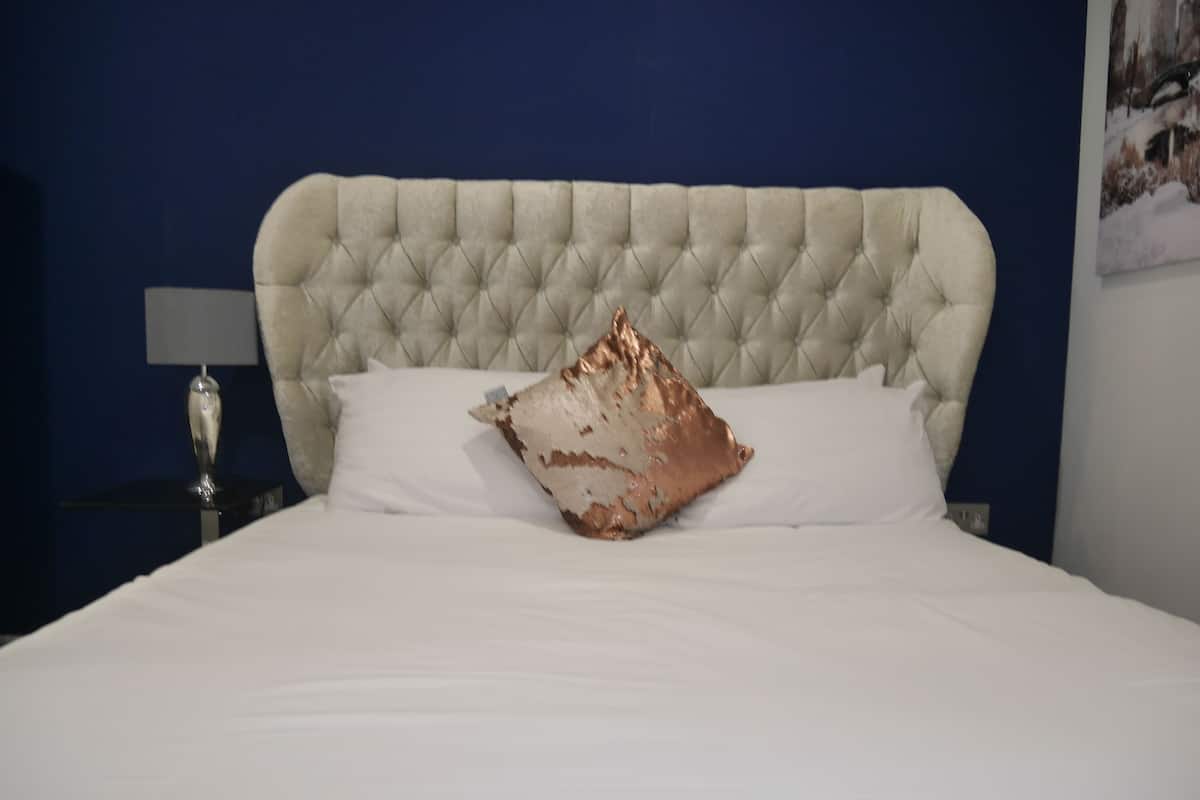 A bed with a tufted headboard, white bedding, and a decorative pillow.