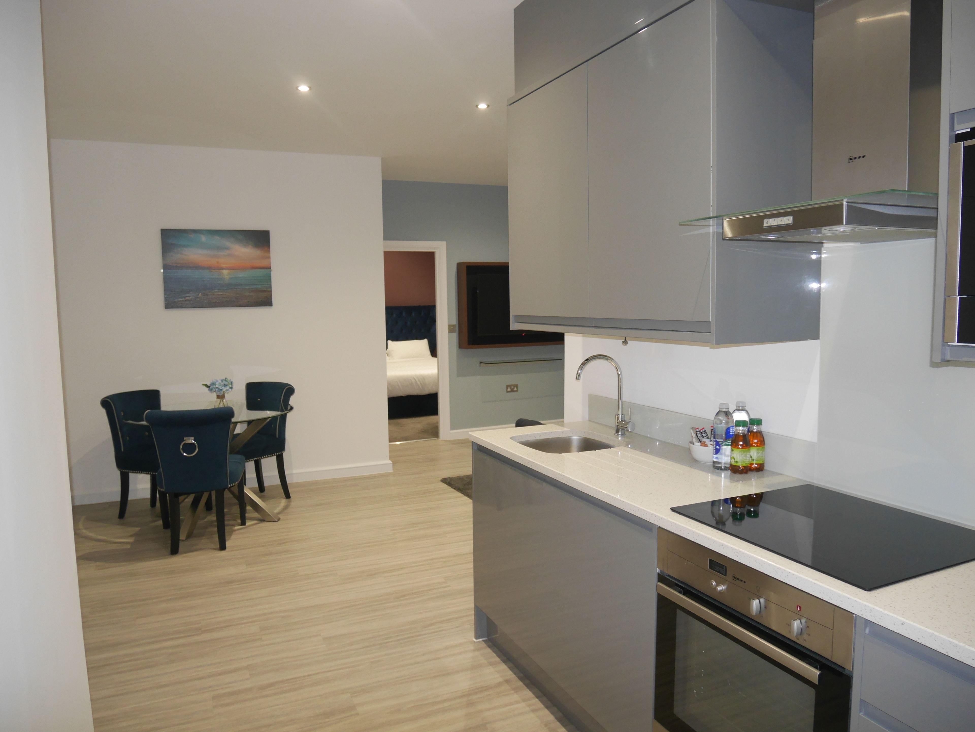A modern kitchen with a built-in oven, a sink, and a dining area with two chairs.