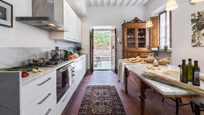 Una cocina moderna con armarios blancos, una estufa y un comedor con una mesa lista para comer.