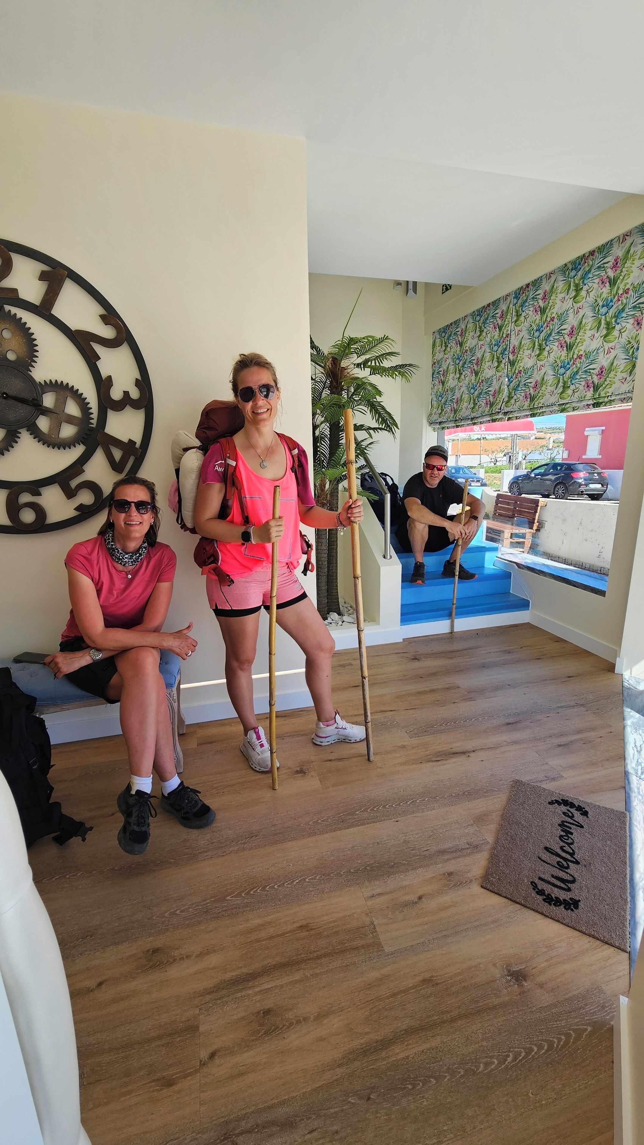 Un vestíbulo de hotel con piso de madera, un reloj de pared grande y un felpudo.
