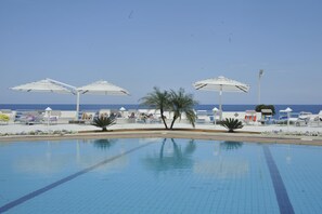 A swimming pool with lounge chairs and umbrellas, surrounded by a clear sky and a calm sea. - La Marsa Vacances (Palermo)