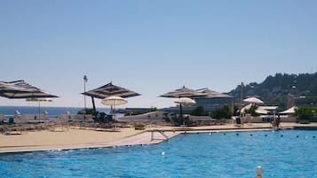 Una piscina al aire libre de temporada, sombrillas