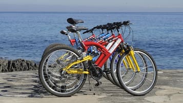 Een rode en gele mountainbike geparkeerd op een beton oppervlak aan zee.