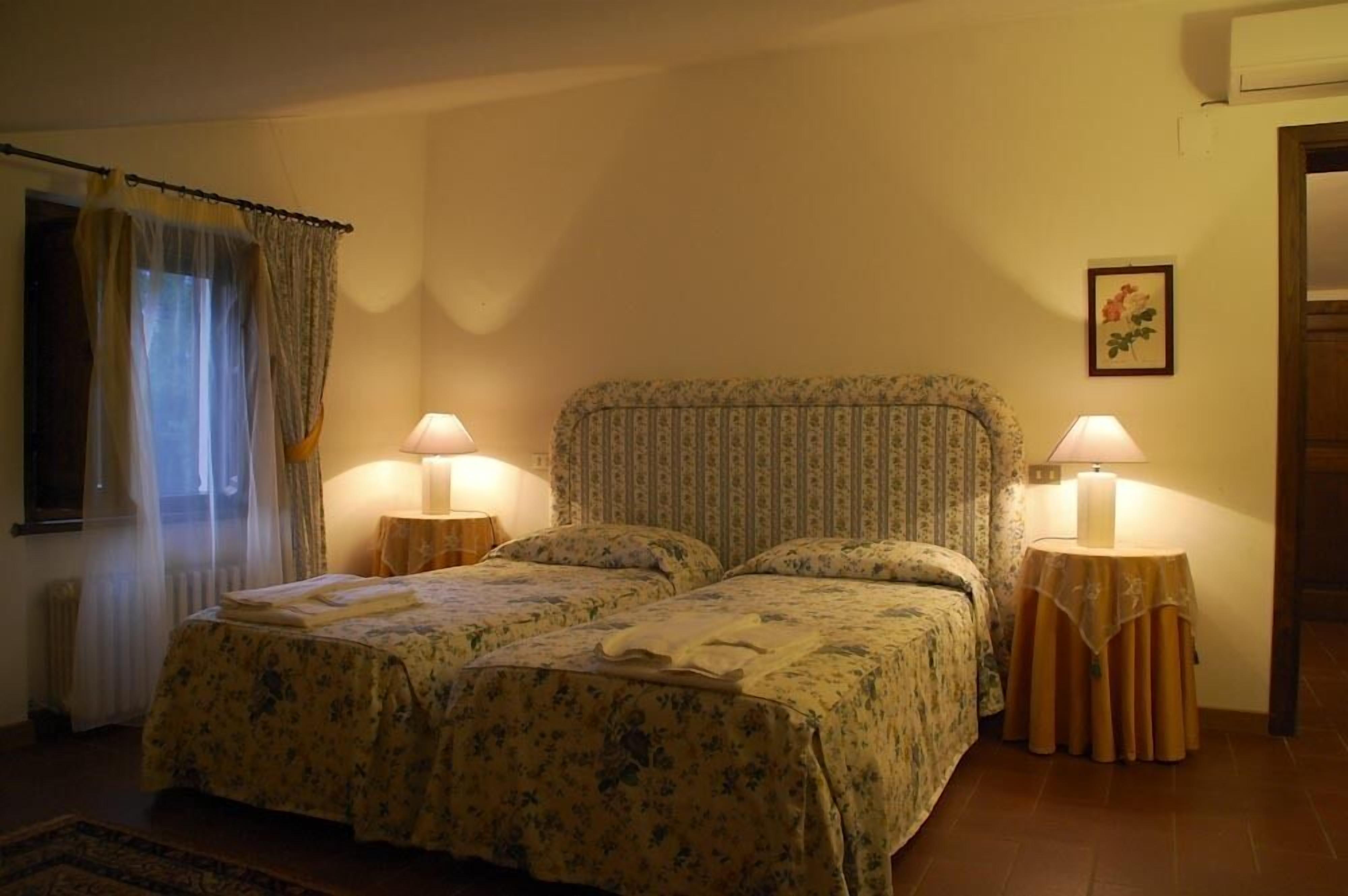 Une chambre avec deux lits, une fenêtre avec des rideaux et deux lampes de chevet.