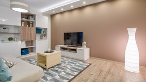 Moderni olohuone, jossa on sohva, TV-taso, hyllyt ja kuviollinen matto.