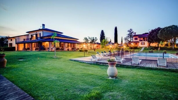 Une maison moderne dotée d’un grand patio, d’une piscine et d’une pelouse bien entretenue.