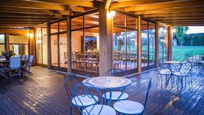 Une terrasse extérieure avec un plancher en bois et des tables et chaises en métal.