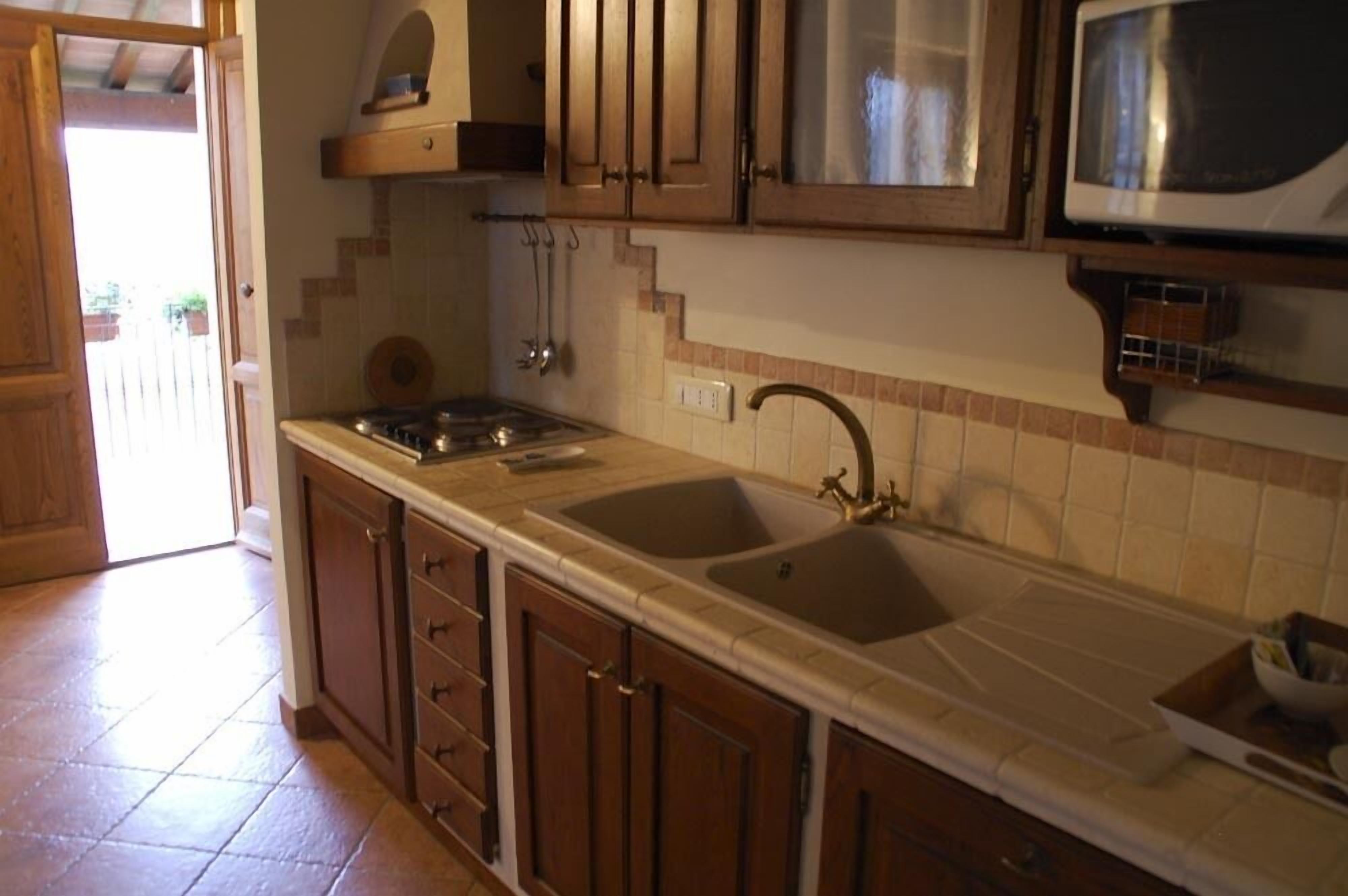 Une cuisine avec des meubles de rangement en bois, un évier à deux bacs et une cuisinière.