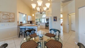 Una cocina moderna con una isla central, taburetes de bar y una mesa de comedor con sillas.