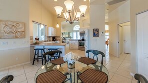 Una cocina moderna con una isla central, taburetes de bar y una mesa de comedor con sillas.