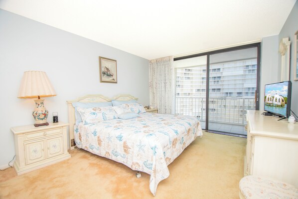 A bedroom with a bed, nightstand, lamp, and a television.