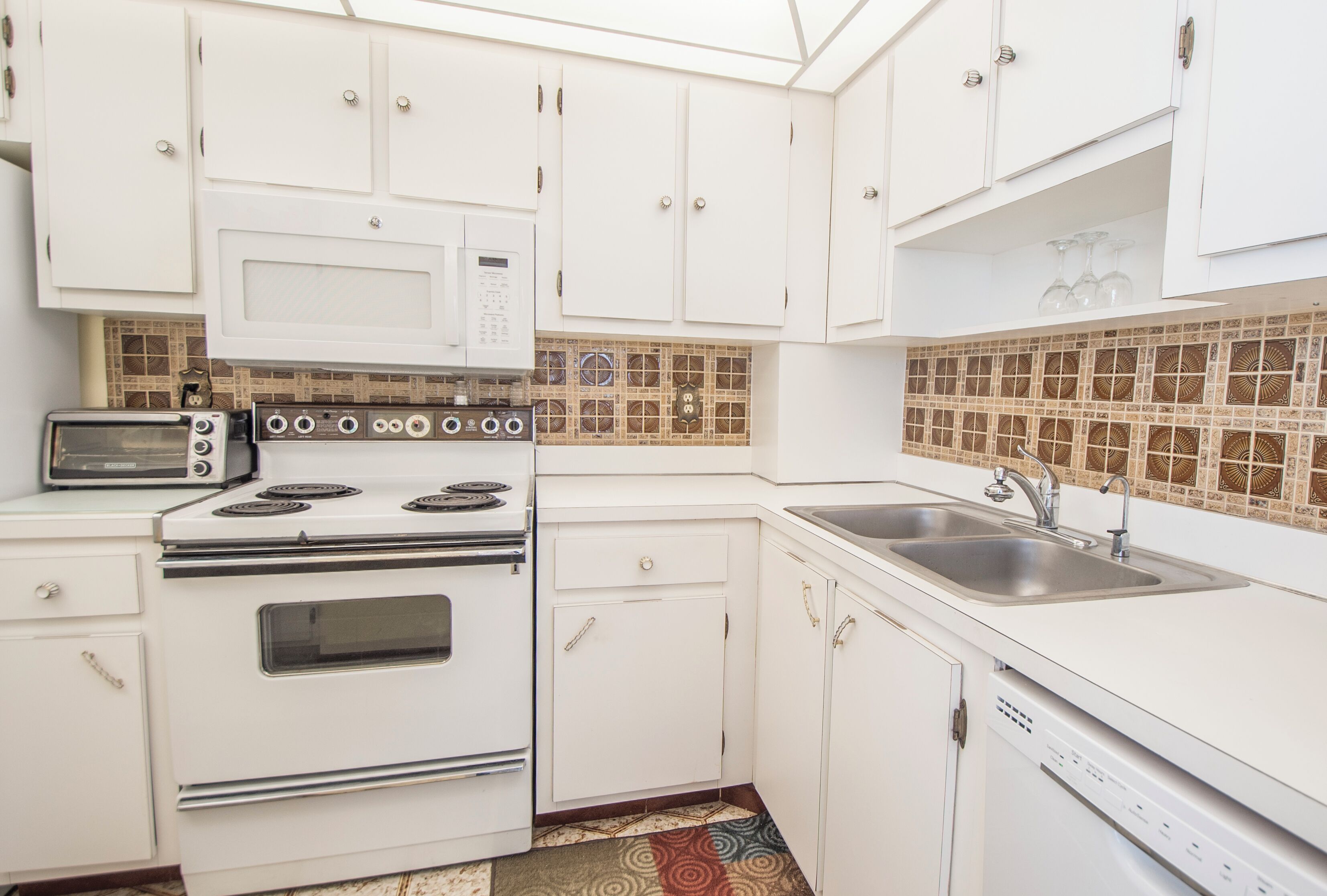 A kitchen with white cabinets, a microwave, stove, and dishwasher.