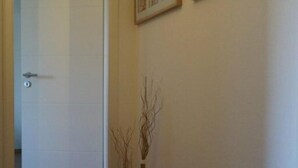 A hallway with wooden flooring, a white door, and two framed pictures on the wall. - Strandleben Fehmarn - Ferienwohnung Ost (Fehmarn)