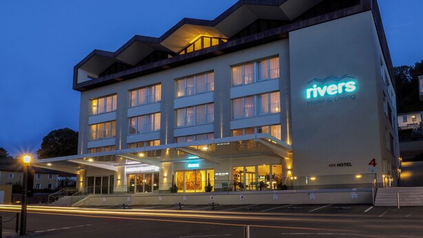 Edificio de Rivers Hotel & Living con diseño moderno, varios pisos y una entrada bien iluminada.