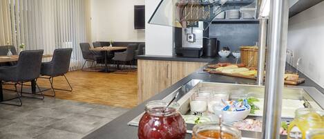 A modern kitchen with a buffet setup, including jars of condiments and a variety of food items.