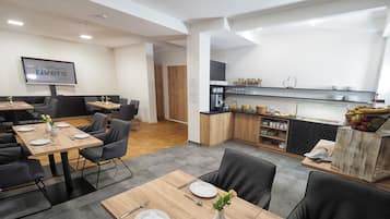 Un comedor de hotel moderno con mesas de madera, sillas negras y un mostrador de bufé con diversos alimentos.