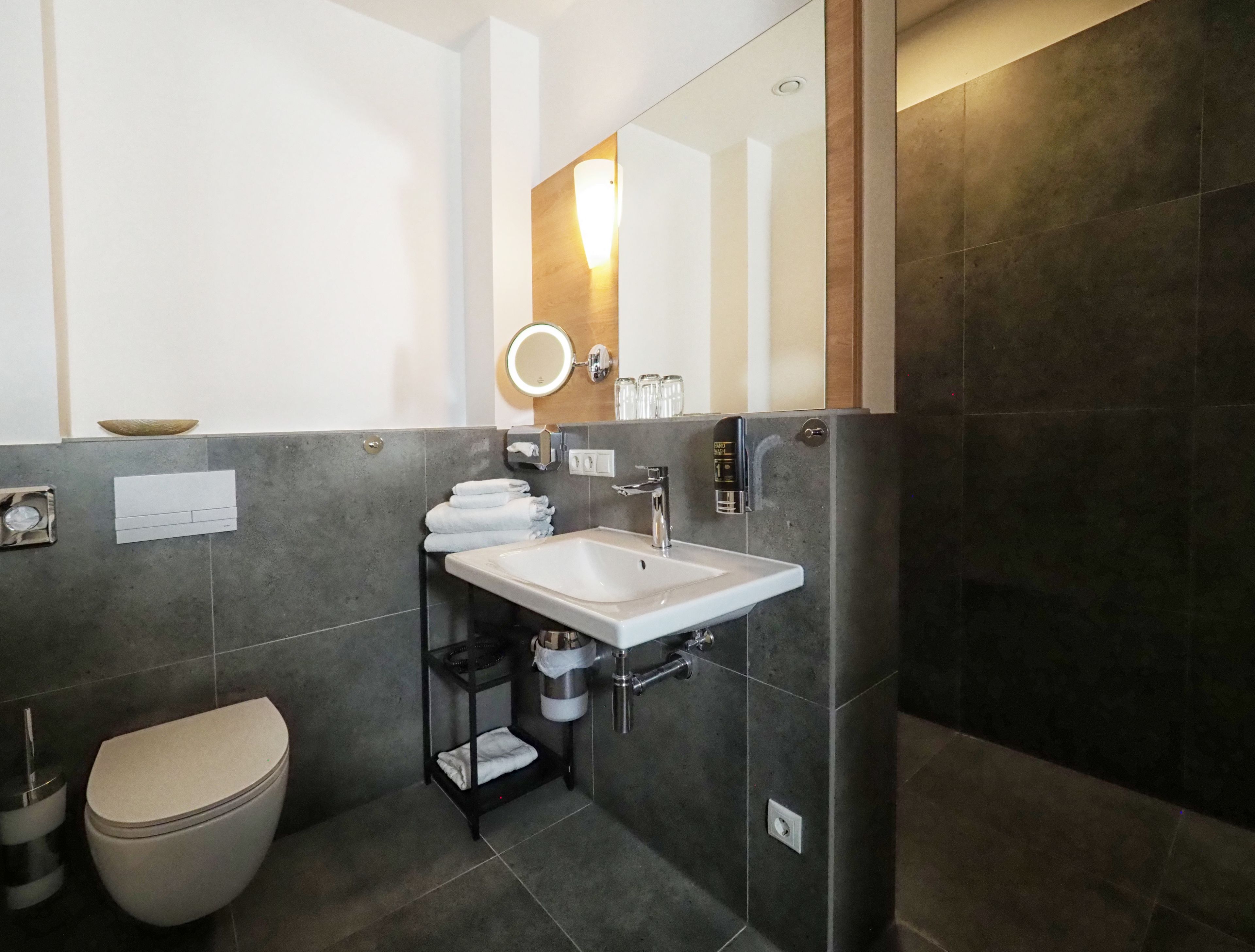 Un baño moderno con un lavabo blanco, un inodoro y un espejo grande.