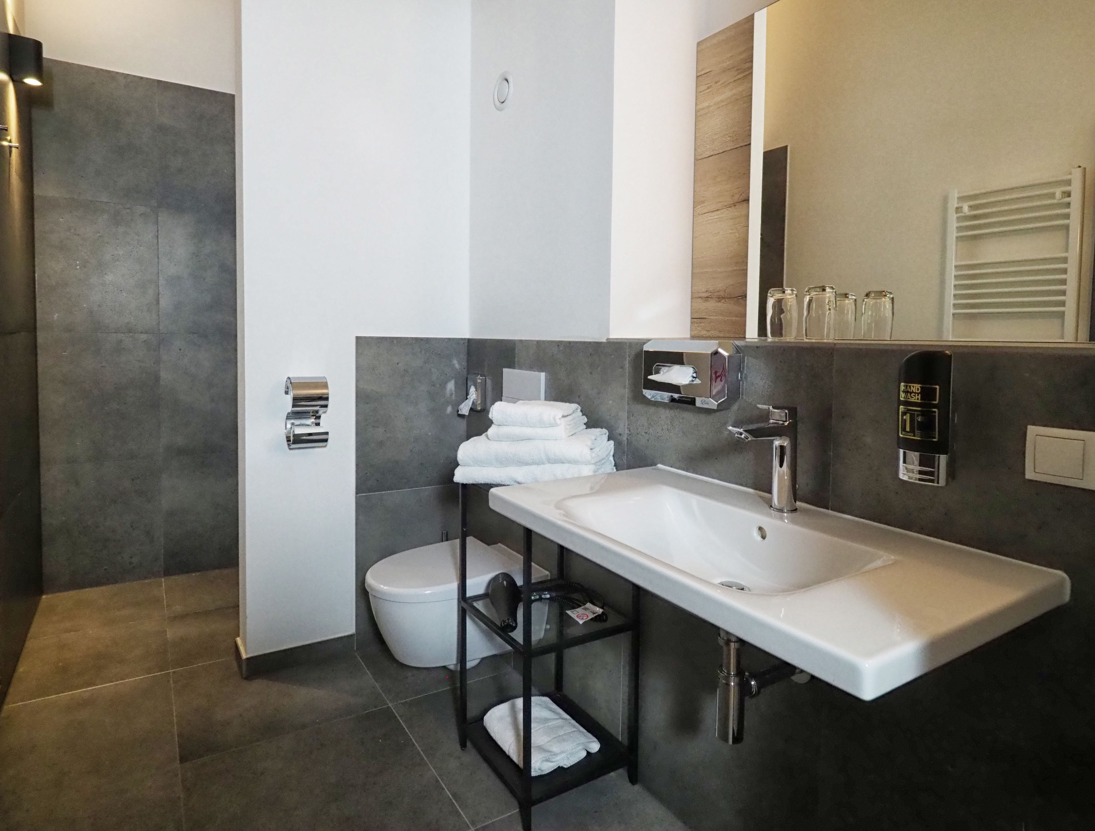 Un baño moderno con un lavamanos blanco, un inodoro y un perchero para toallas.