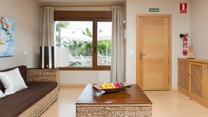A room with a wooden door labeled "SALIDA," a wicker sofa, a wooden table with a fruit bowl, and a view of outdoor furniture through a window. - Side sea view, HEATED POOL, Heating, Wide terrace, Free wifi (7) (La Matanza de Acentejo)