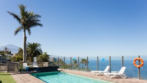 A pool with clear blue water, surrounded by white lounge chairs and a palm tree. - Side sea view, HEATED POOL, Heating, Wide terrace, Free wifi (7) (La Matanza de Acentejo)
