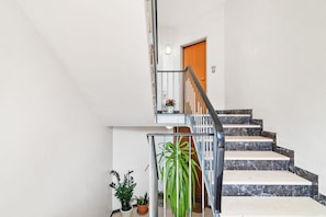 A staircase with a metal railing, a potted plant, and a door at the top.