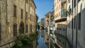 Un canal étroit bordé de bâtiments historiques dotés d’arcs en plein cintre et de balcons.
