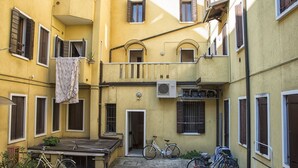 Une cour avec un vélo, un banc et un bâtiment doté de nombreuses fenêtres et de balcons.