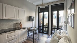 Une cuisine moderne avec des meubles blancs, un plan de travail noir et un coin repas comprenant une table et des chaises.
