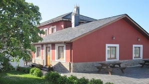 Punainen rakennus, jossa on kivinen sokkeli, savupiippu ja kivetty patio, jossa on piknikpöytiä.