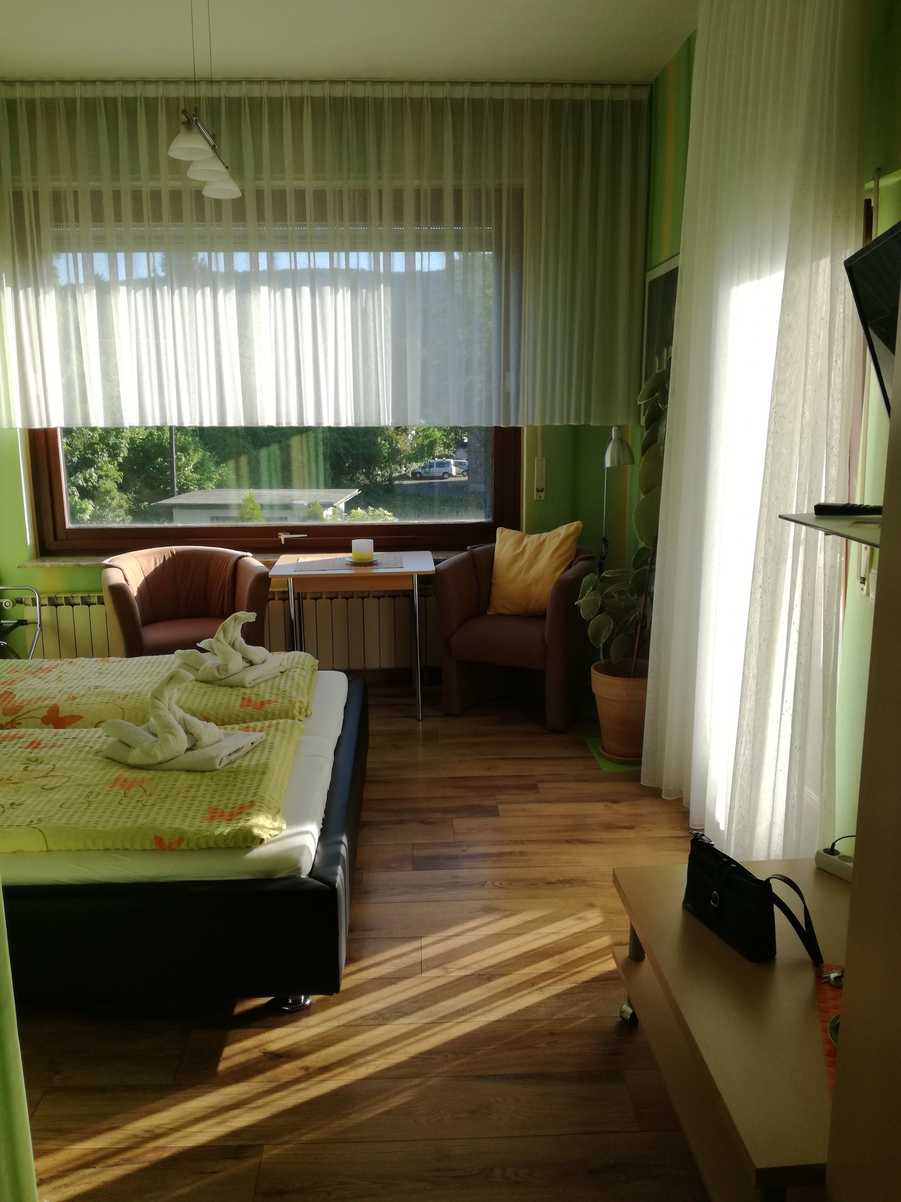 A hotel room with a bed, a desk, a chair, a television, and a window with a view of the outside.