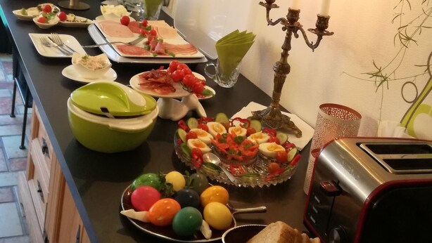 A buffet table with various food items, a candelabra with candles, and a toaster. - Pension Carmen (Bad Hoenningen)