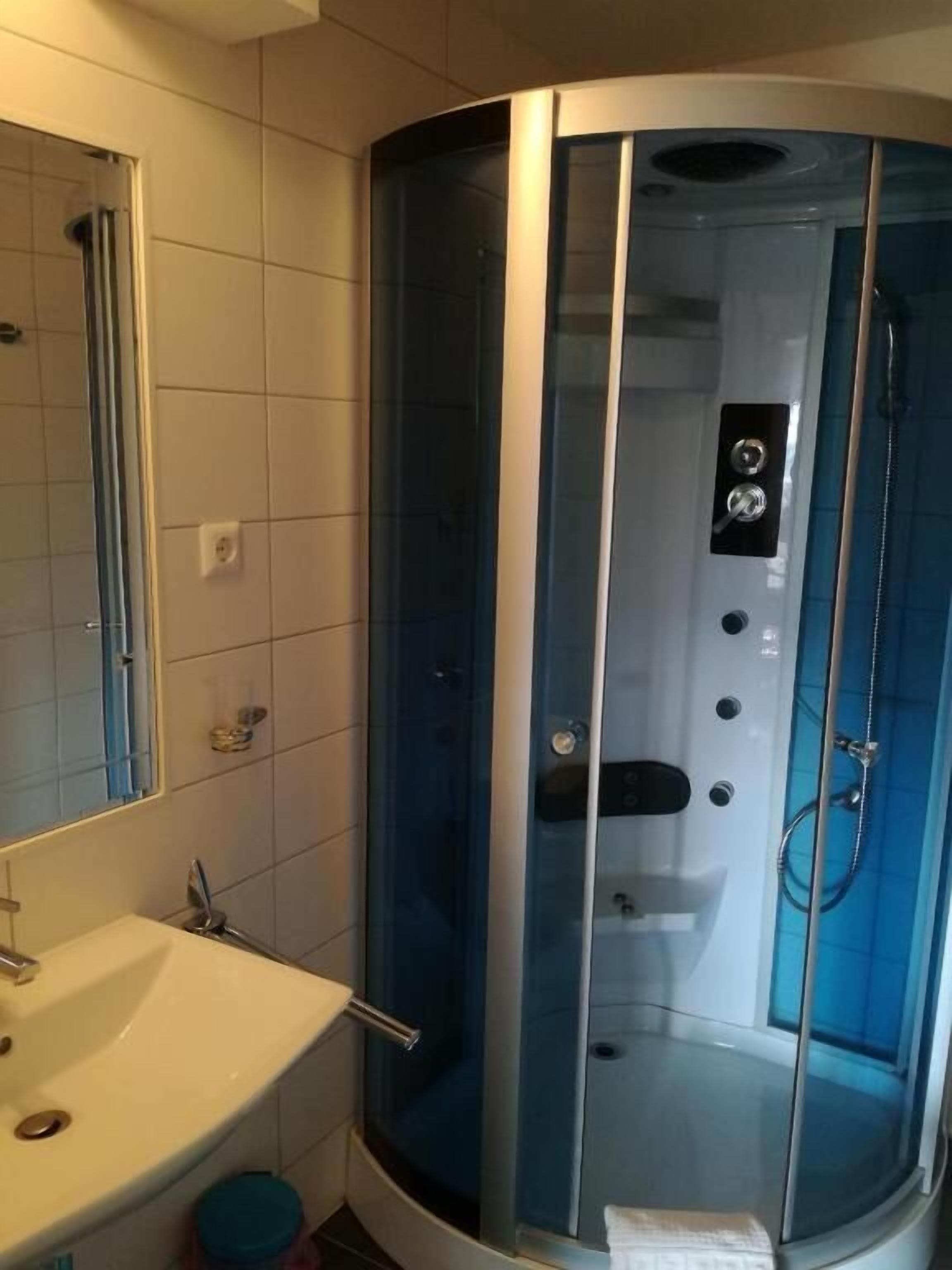 Ein Badezimmer mit Duschkabine, Waschbecken und Spiegel.