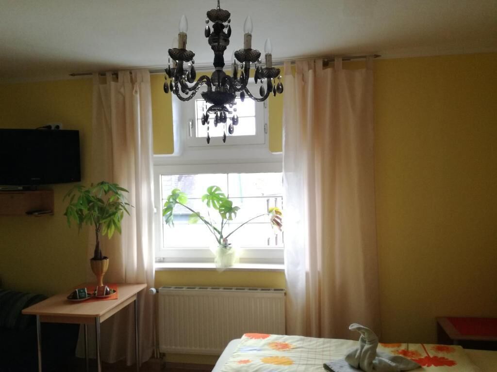 A room with a bed, a desk, a television, and a window with curtains.